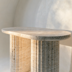 The Fluted Oval Coffee Table in warm ivory travertine — fluted cylindrical column legs, honed finish