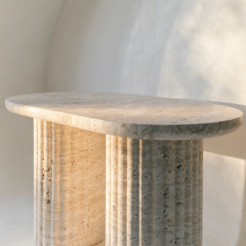 The Fluted Oval Coffee Table in warm ivory travertine — fluted cylindrical column legs, honed finish