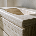 The Carved Travertine Vanity — integrated basin carved into warm ivory travertine, flush drawers, honed finish