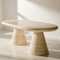 The Oval Travertine Dining Table — warm ivory travertine, cone-form column pedestals, horizontal geological banding