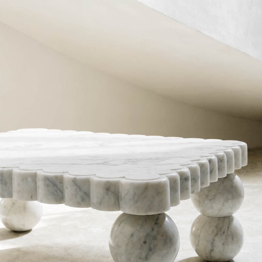 The Scalloped Coffee Table in Bianco Carrara marble — carved scalloped perimeter edge, sphere legs